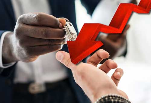 How Mold Impacts Price and Negotiations. Image of an ongoing sale of a home with they seller handing over keys to a buyer. A red downward arrow depicting decline in price.