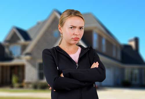 a lady cautiously standing in front of a house